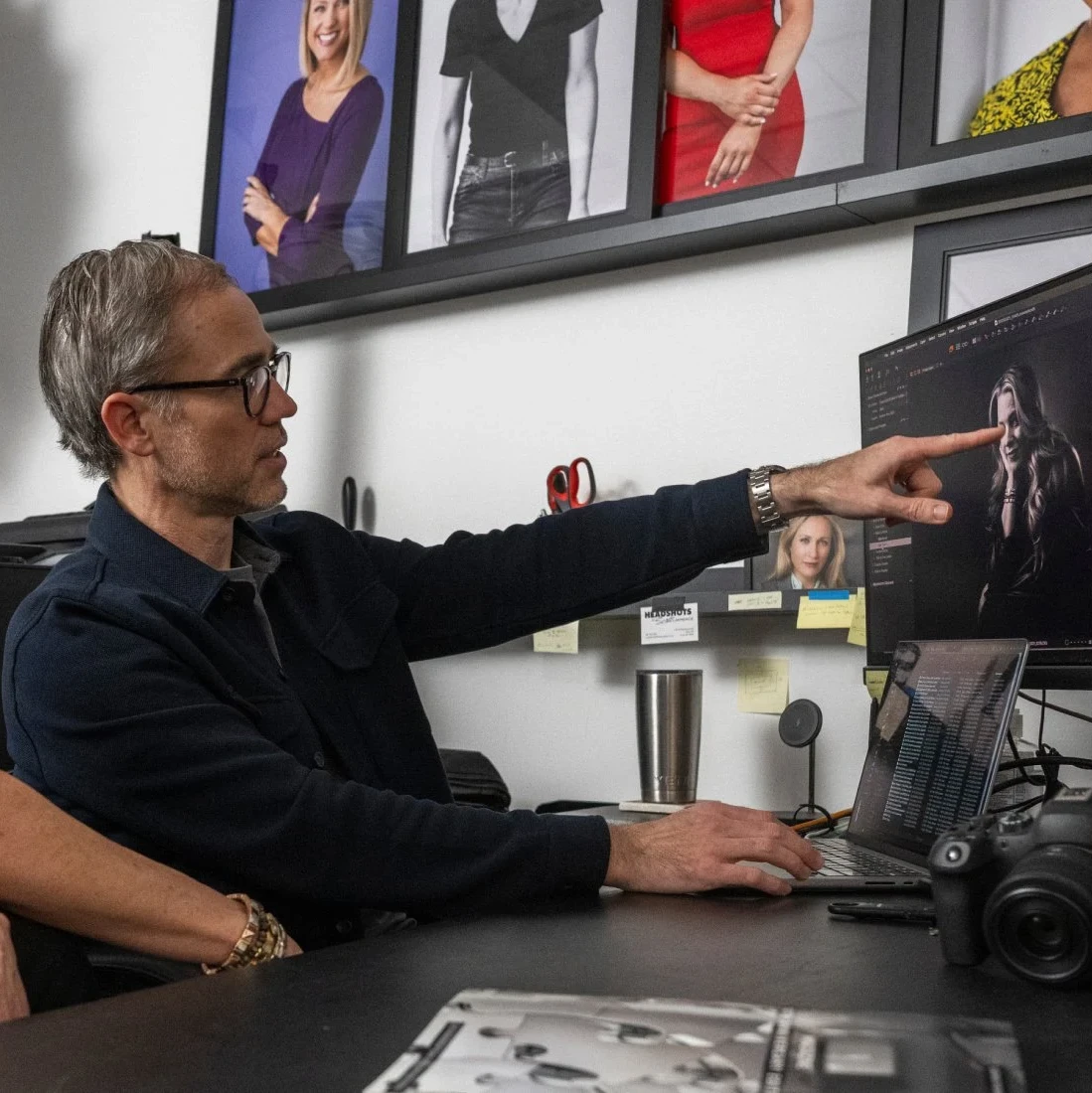 Man with gray hair and glasses poses for the camera in a photography studio