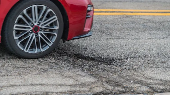 A photograph of a vehicle encountering a pothole on a city street, used to illustrate the City of Memphis case study. The image highlights the real-world infrastructure challenges that the city addressed by partnering with Google to use AI and street-view imagery to proactively identify and repair road damage.