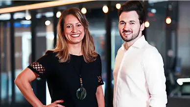 Founders Tatiana and Everton pose in front of an office space