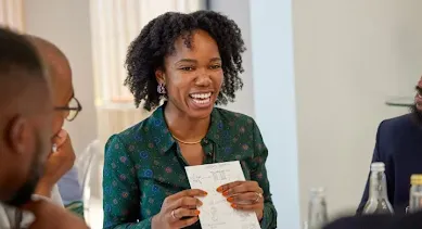 A lady showing paper in a group and laughing.