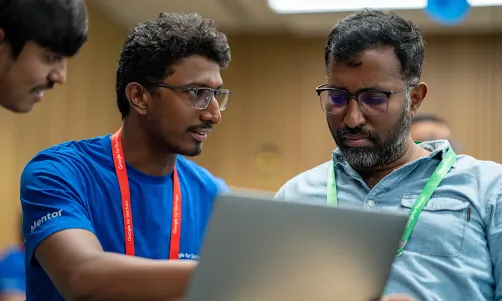 A man wearing red lanyard explaining something to other man who wore green lanyard .