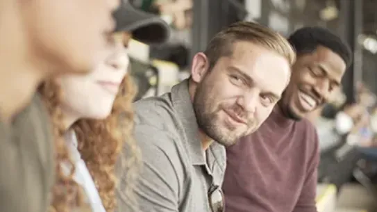 group of friends with the camera focused on one man smiling
