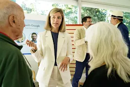 Laurie Richardson, Google’s VP of Trust and Safety, engaging in conversation with attendees at the 2023 Aspen Security Forum. She is wearing a white suit and gesturing while speaking. In the background, "Safer with Google" signage and other forum participants are visible under a bright outdoor tent.