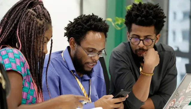 A man and woman using mobile and other man looking into it