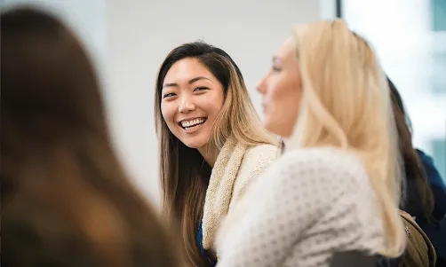 A lady in the group is looking at another lady with a smile.