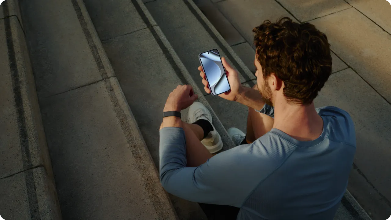 A man wearing a Google Fitbit Air checks his phone