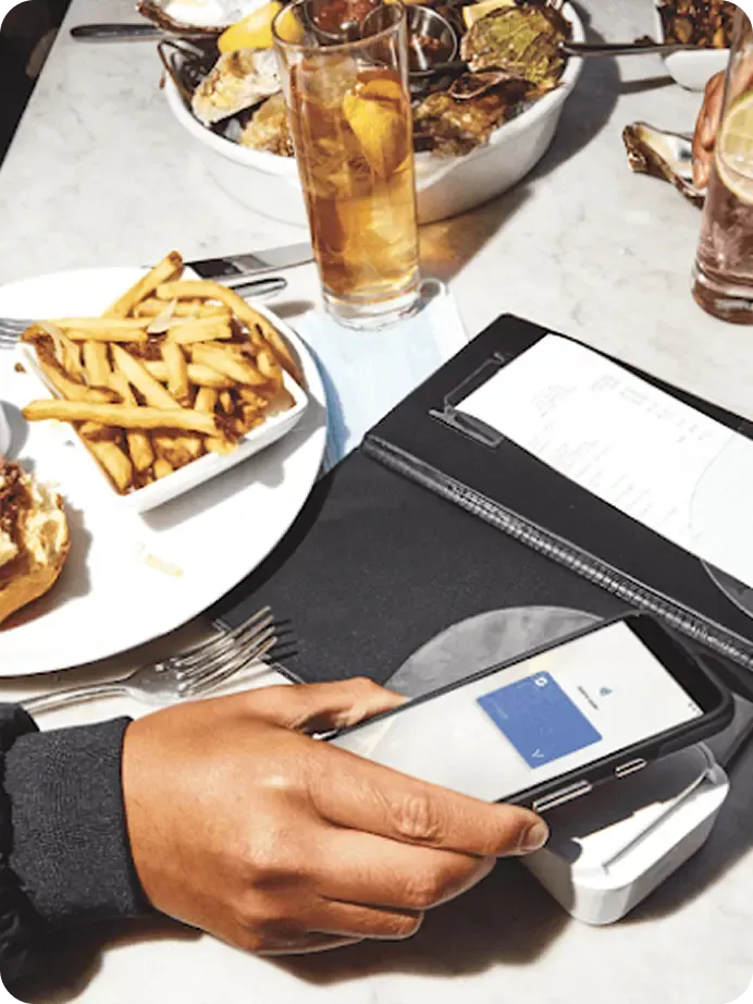 Half eaten hamburger and fries next to an open check at a restaurant