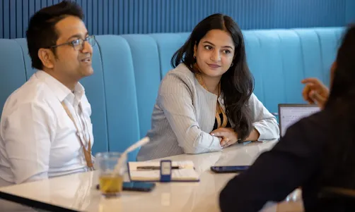 A woman is explaining something to a woman and a man.