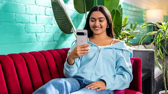 Woman sitting on bed with Android phone
