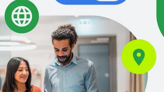 A woman with long dark hair and wearing a red shirt clutches a tablet and smiles while standing next to a taller man in a blue button-up shift, also holding a tablet and gesturing at the screen.