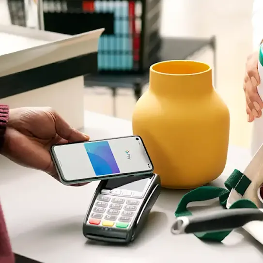 A person using a smartphone to make a Tap and Pay contactless payment at the checkout counter.