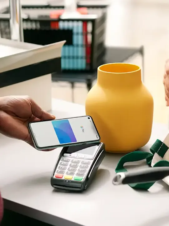 A person using a smartphone to make a Tap and Pay contactless payment at the checkout counter.