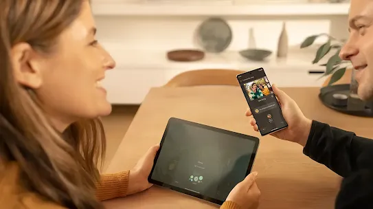 Man and woman using their devices, he uses a smartphone and the woman uses a tablet. 