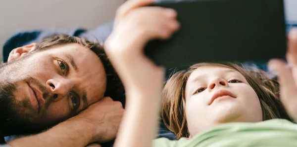 A father and son watch a video on a phone together.