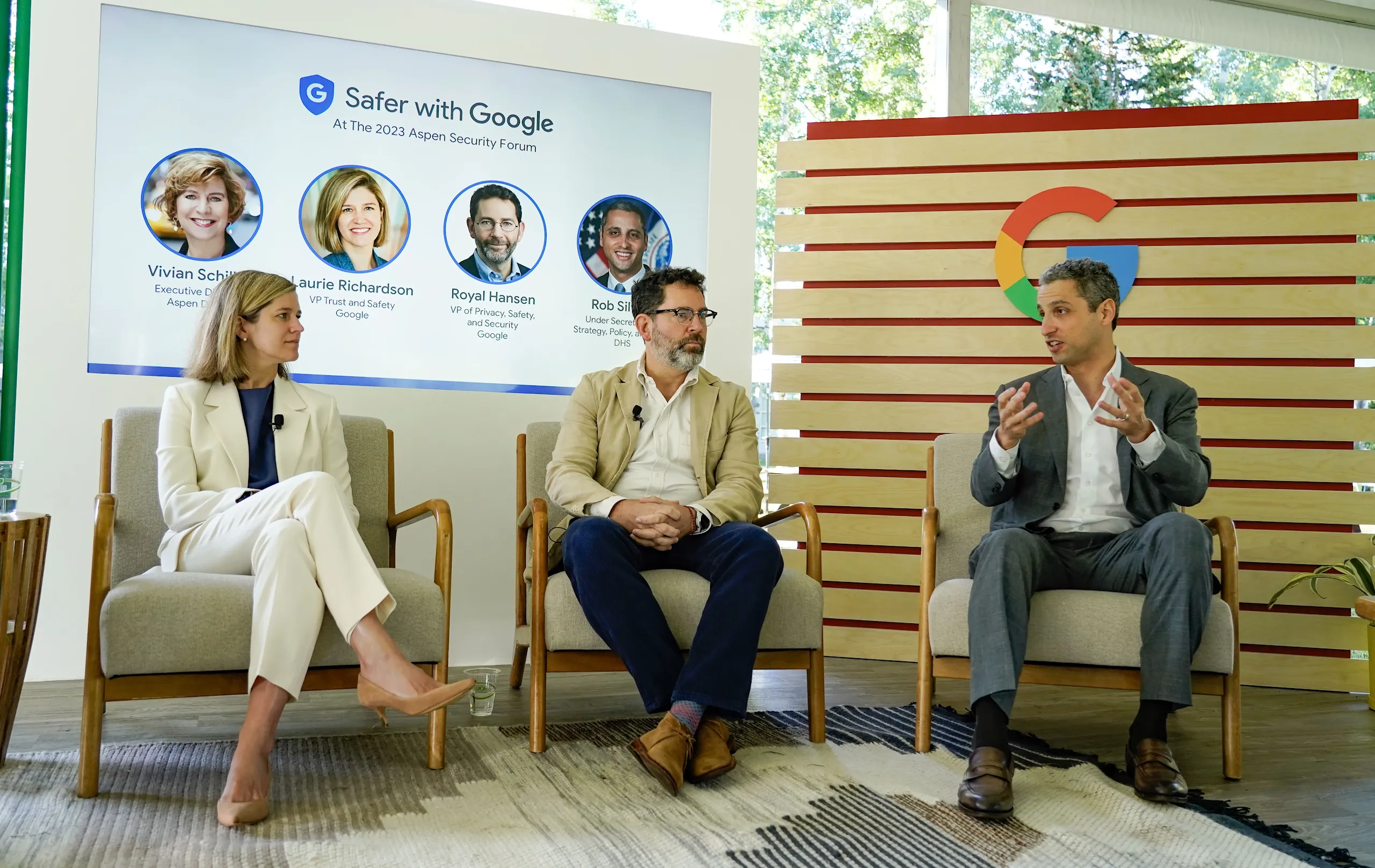 Laurie Richardson (VP Trust and Safety, Google), Royal Hansen (VP Privacy, Safety, and Security, Google), and Rob Silvers (Under Secretary for Strategy, Policy, and Plans, DHS) sit in armchairs for a "Safer with Google" panel at the 2023 Aspen Security Forum. Behind them, a screen displays the event title and headshots of the speakers, alongside a modern wooden wall featuring the Google "G" logo.