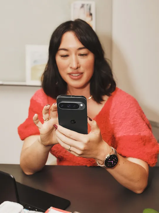 A person sits at a desk and holds a Pixel phone.