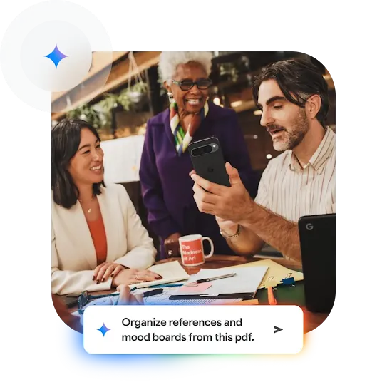 Work colleagues around a table with a notepad and pens excitedly look at someone’s phone.