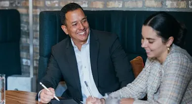 Man in Blazer Holding a Pen and looking at lady.