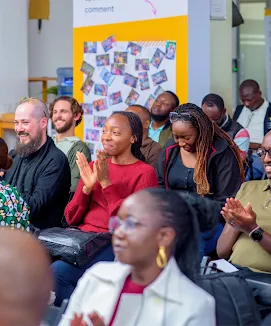 Audience members smiling and applauding at a professional workshop.