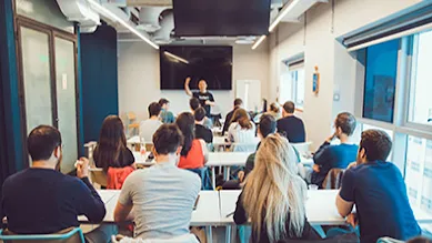 Founders sit at desks in a Google for Startups Campus Tel Aviv classroom, looking up at Google product expert at front of room.