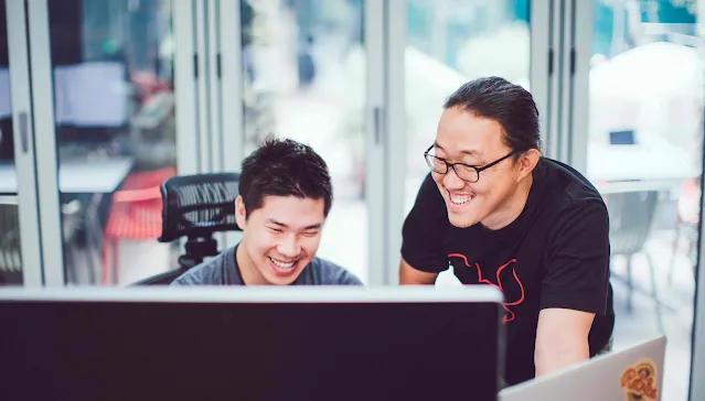 2 men sitting around a round table, laughing.