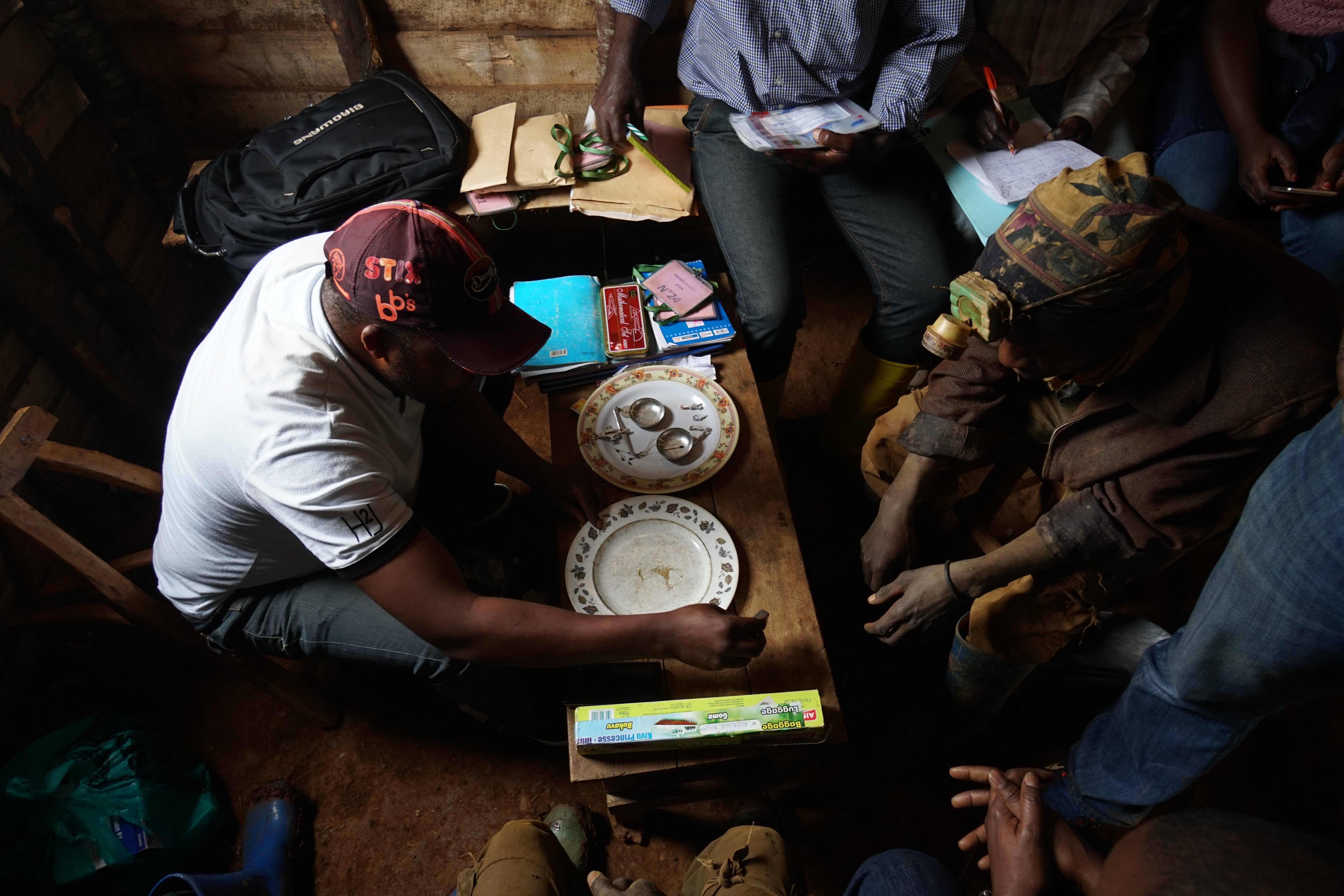A group of people gathered around the table using recording gold transactions, supporting traceability.