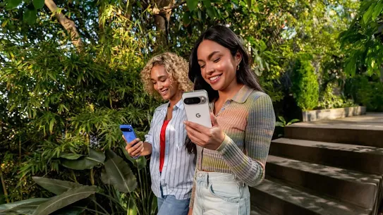 Two women using their Android devices outdoors, with trees in the background.