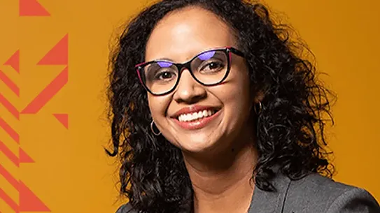 Retrato de Flávia Garcia sobre fundo laranja, com padronagens triangulares.