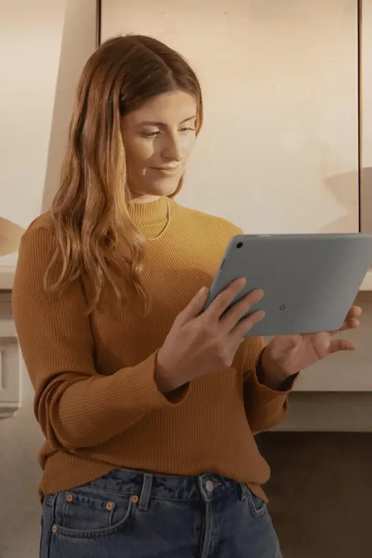 A lady smiling while looking at her tablet’s screen.