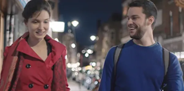 Founders, Elina and Adam, are walking along a sidewalk at night.