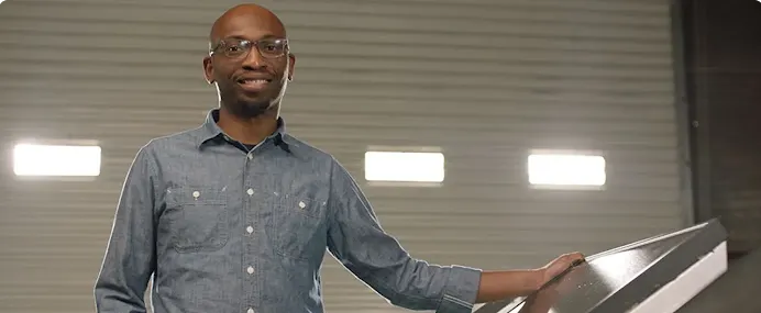 Founder Seyi Fabode smiles at the camera inside his garage-turned-office.