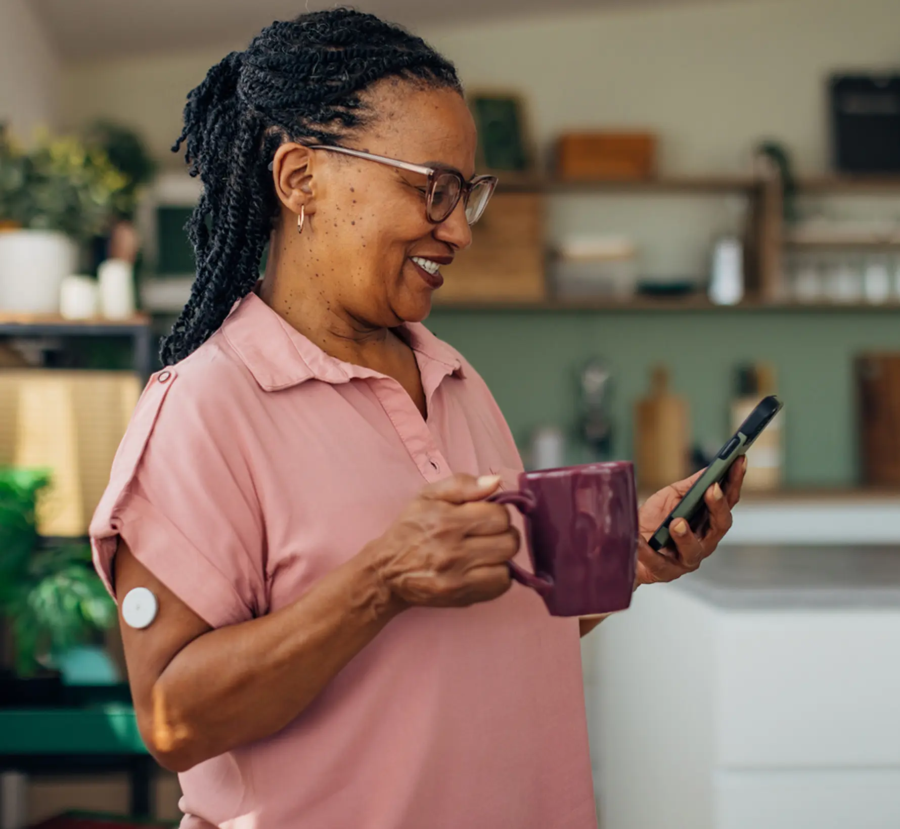 Image of woman wearing Google Fitbit Air and checking her glucose monitor data in the Google Health App. 